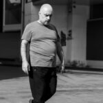 Stor eller høj Monochrome street scene with a man walking, urban background.